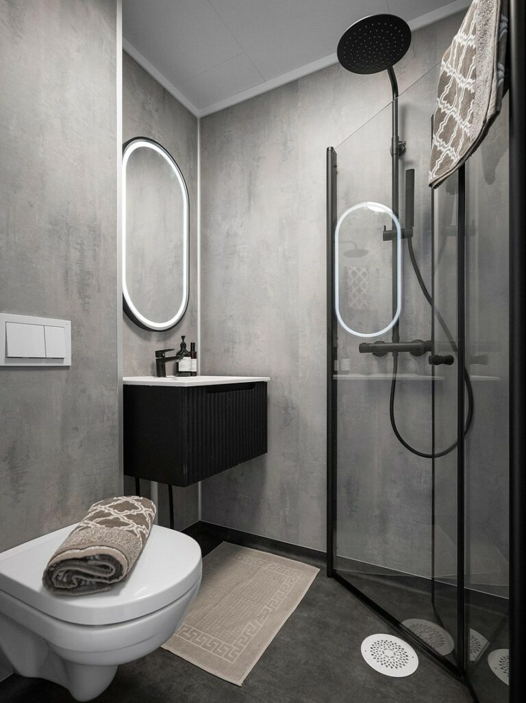 Projet de rénovation de salle de bain (carrelage effet béton, mobilier noir suspendu et miroir ovale LED), réalisé par PRO BAT-IM, à Val-de-Marne.
